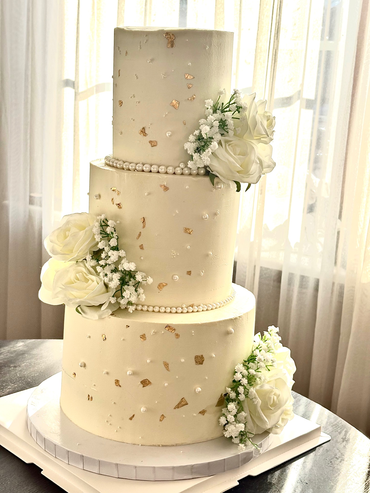 Elegante witte bruidstaart met gouden blad en verse bloemen